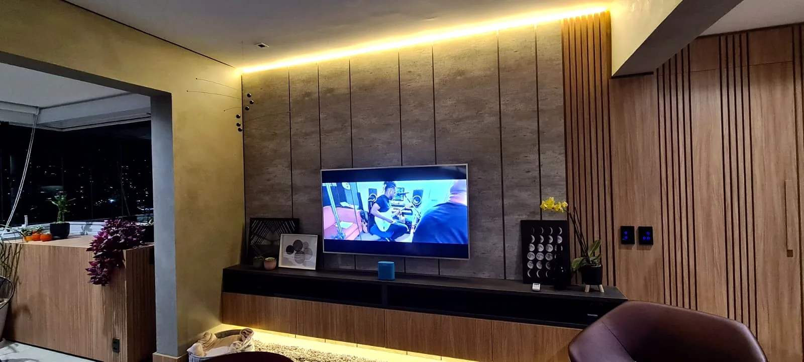 Painel de TV ripado em madeira com iluminação LED e móveis planejados em apartamento, projeto da Oficina 306 em São Paulo